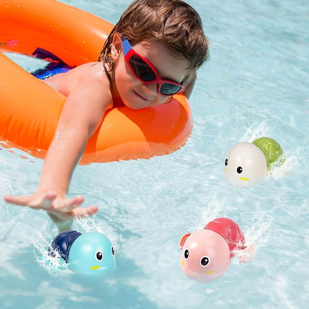 Child in a pool float reaching toward three wind-up turtles swimming nearby.