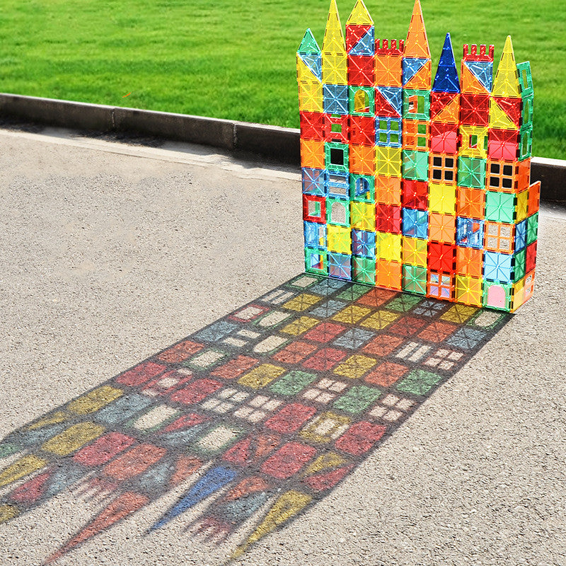 Colorful translucent magnetic tile castle built on pavement with sunlight shining through