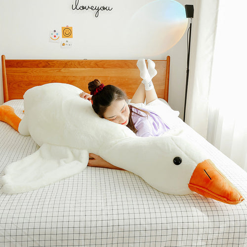 Person resting beside a long white goose plush