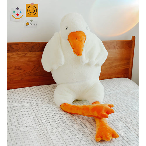 Large white goose plush seated on a bed
