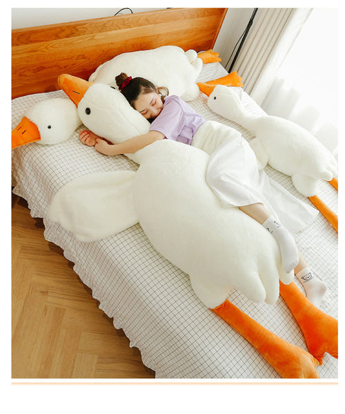Person reclining among several white goose plush toys