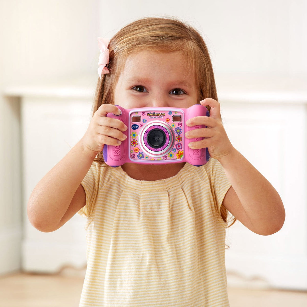 Child holding a pink camera to take a picture