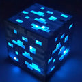 Glowing blue pixel ore block night light photographed in the dark.
