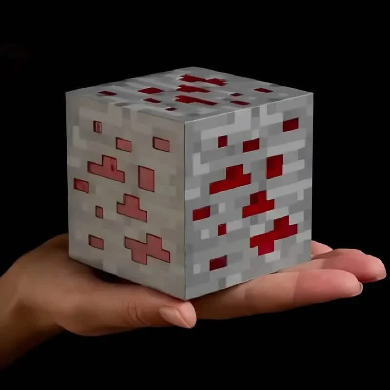 Hand holding a gray pixel ore block light with glowing red crystal pattern.